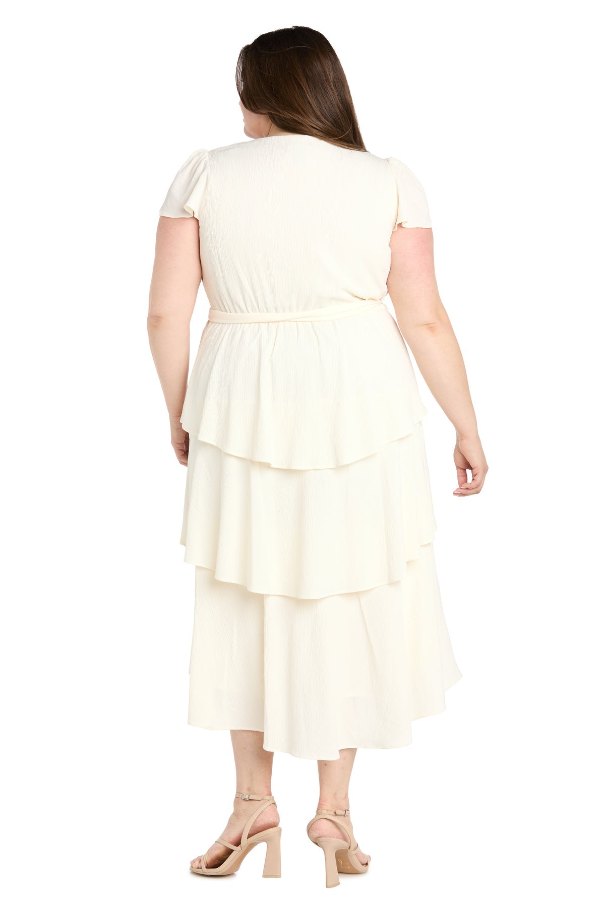 A woman is seen from behind wearing the R&M Richards 6677W Plus-Size White Party Dress, styled elegantly with beige high-heeled sandals.